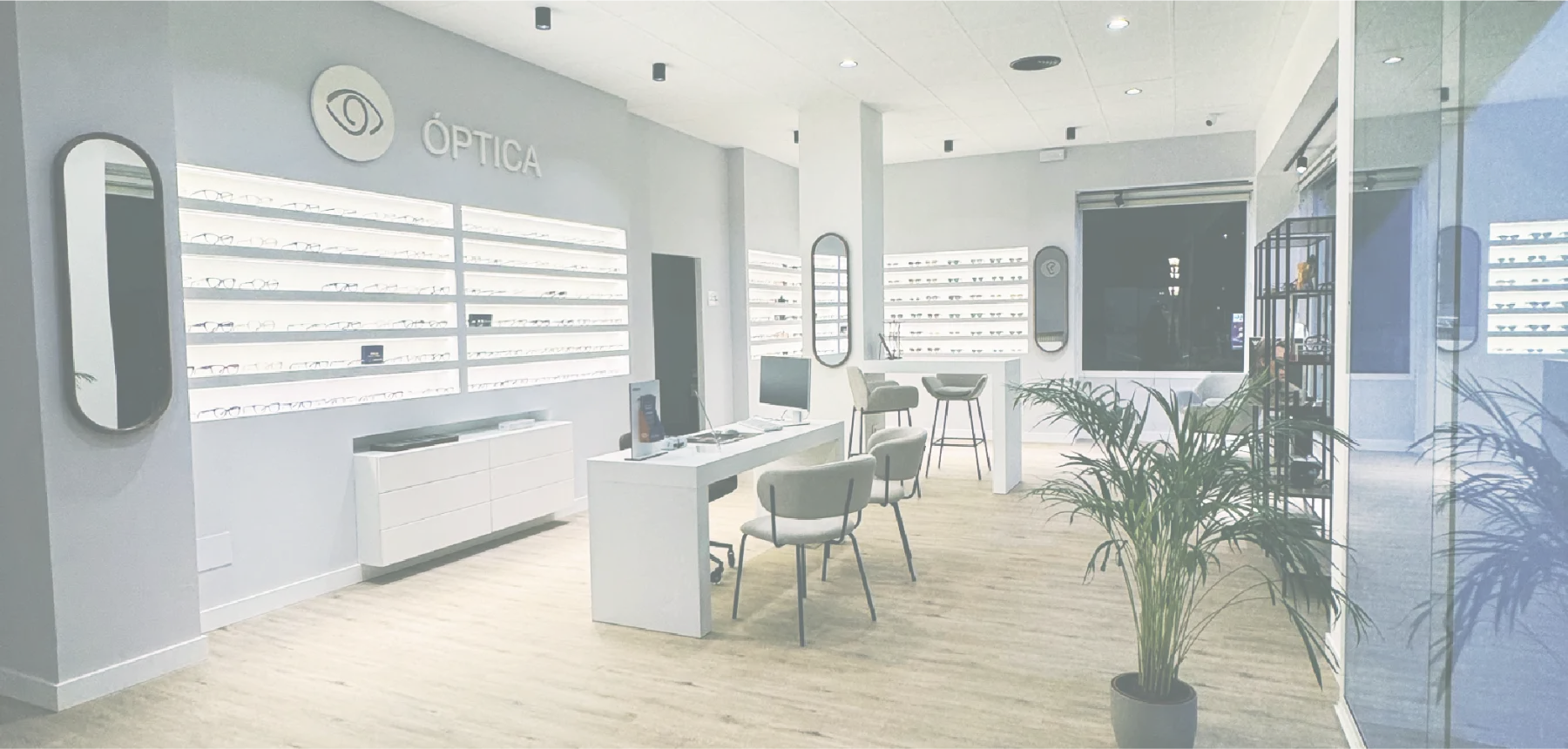 Interior de la óptica: expositores de monturas iluminados y zona de atención