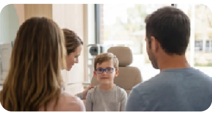 Familia acompañando a un niño con gafas azules en la consulta