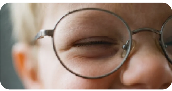 Niño guiñando un ojo tras sus gafas redondas