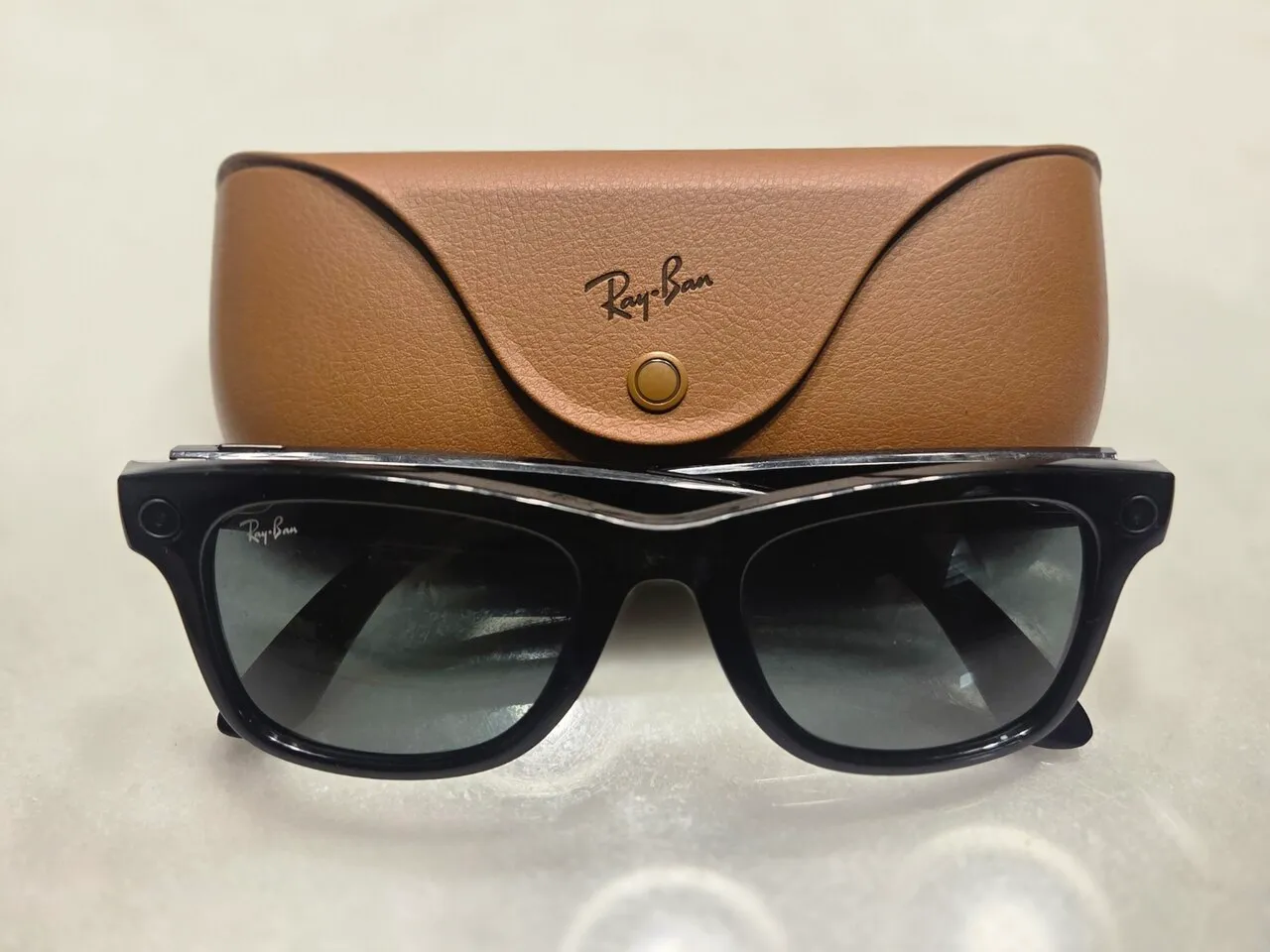 Gafas Ray-Ban Meta Wayfarer negras delante de su funda de carga de cuero